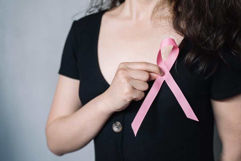 Frau hält eine rosa Schleife über die Brust