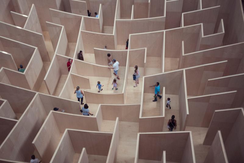 Menschen probieren ein Labyrinth aus und suchen den Ausgang. 