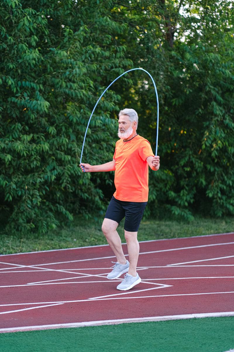 Ein älterer Herr macht Seilsprünge auf dem Sportplatz.