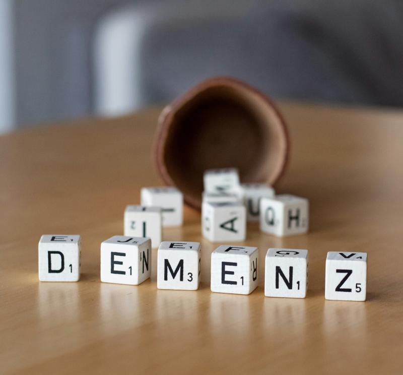 Das Bild zeigt einen Holztisch mit Würfeln und Buchstaben.