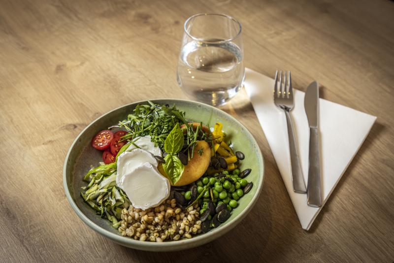 Das Bild zeigt einen Teller mit Salat, Besteck und ein Glas Wasser. 