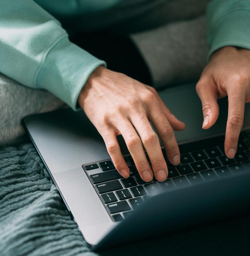 Das Bild zeigt zwei Hände, die auf der Tastatur eines Notebooks tippen. 