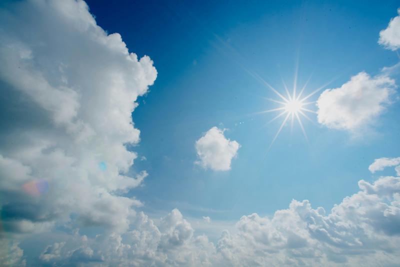 Das Bild zeigt blauen Himmel mit Sonne und Wolken.