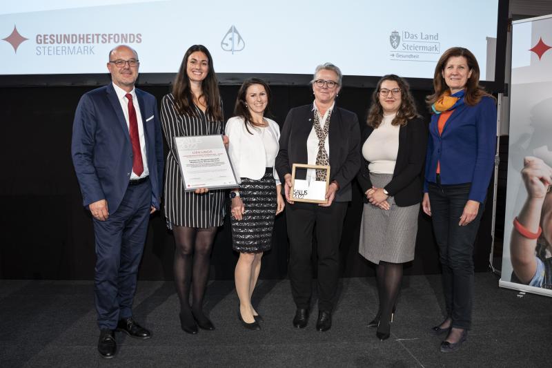 Ein Mann und vier Frauen bei einer Preisverleihung