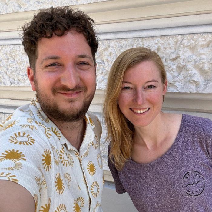 Der Herausgeber des Podcasts Andreas Sator und Podcast-Gast Jana Meixner machen ein Foto vor einem Gebäude