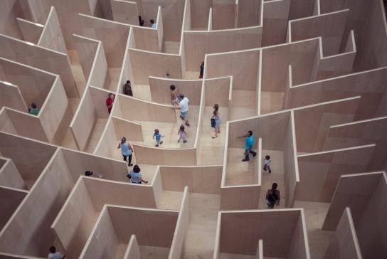 Menschen probieren ein Labyrinth aus und suchen den Ausgang.