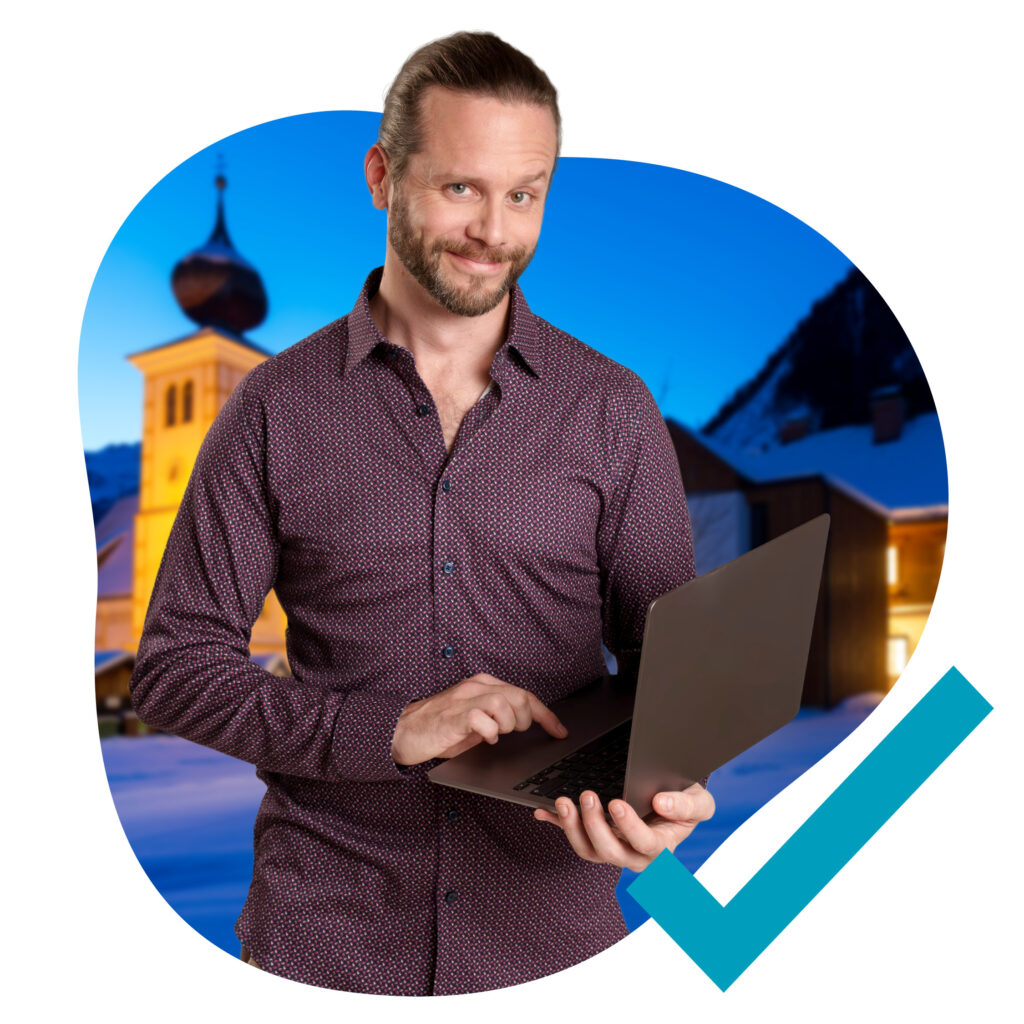 Mann mit einem Laptop in der Hand vor einem Kirchenturm